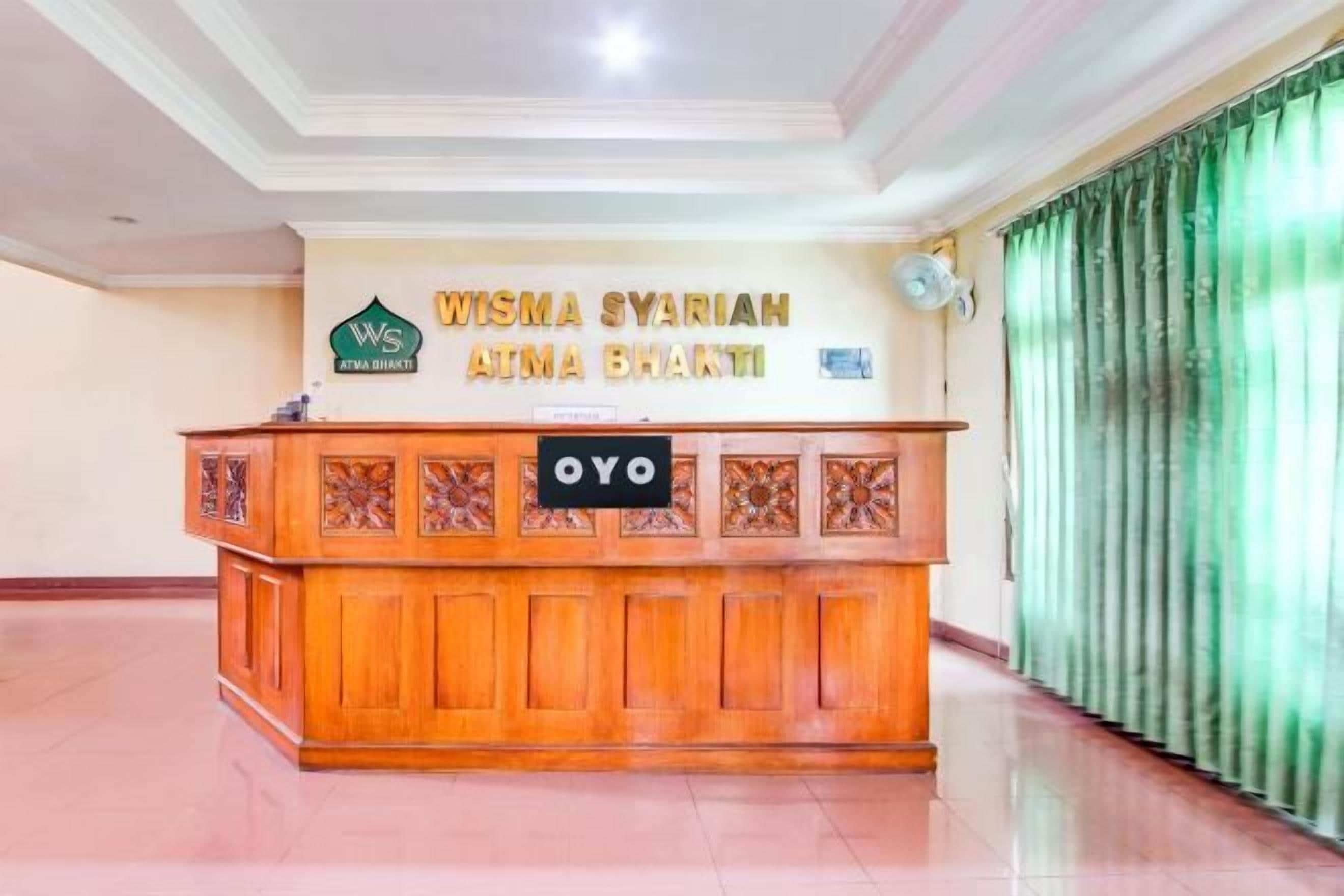 Un comptoir d’accueil avec une enseigne indiquant « Wisma Syariah Amina Bhakti » et un logo.