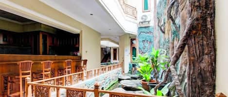 A hotel lobby with a central staircase, wooden seating, and a decorative wall.