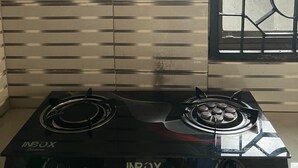 A kitchen with a gas stove labeled "INBOX" and a window with metal bars. - Mashingo Homestay (Dar es Salaam)