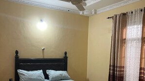 A neatly made bed with a headboard, a ceiling fan, and a light fixture. - Mashingo Homestay (Dar es Salaam)