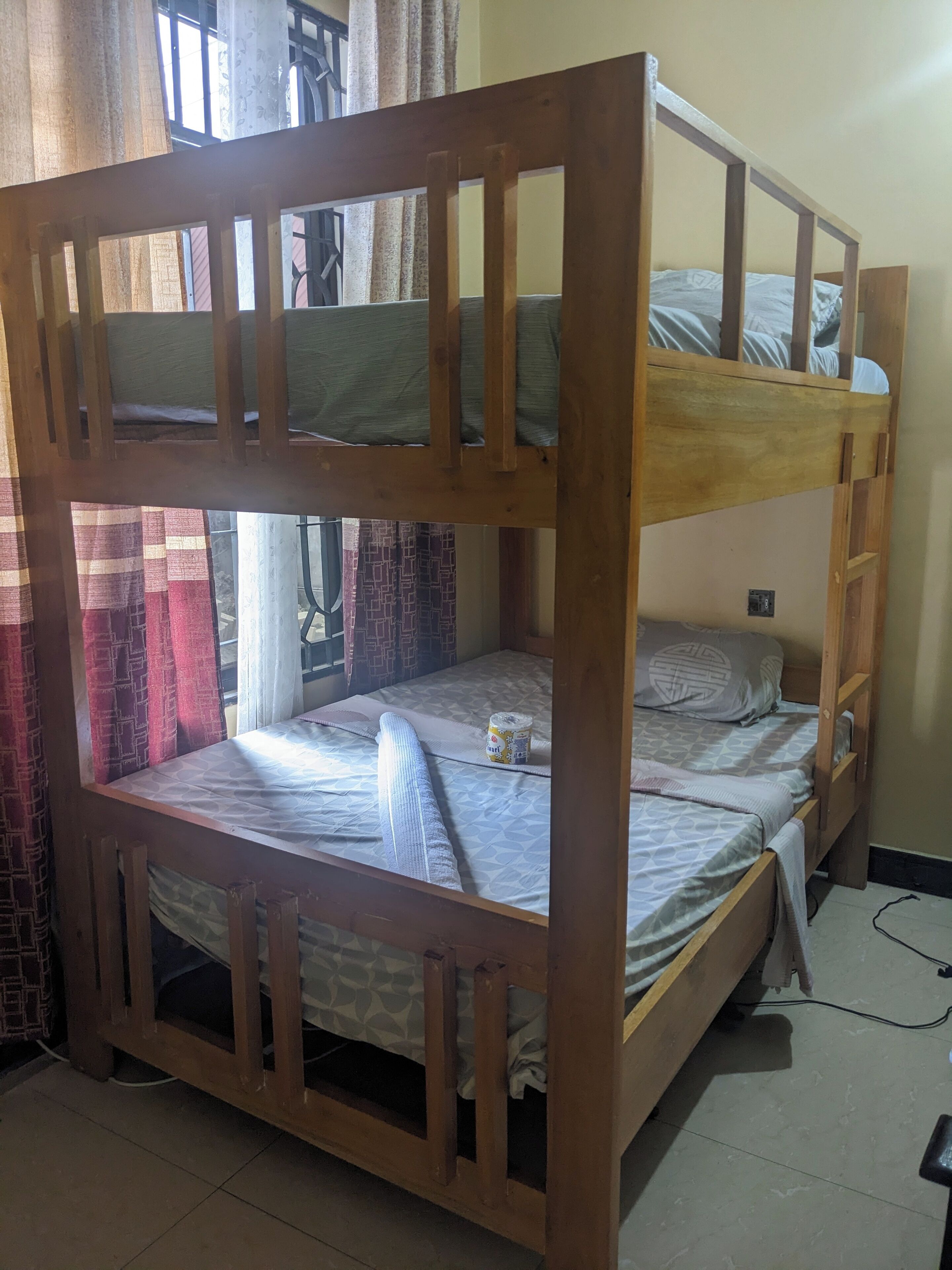 Una cama litera con dos niveles, una mesita de noche pequeña y un enchufe en la cama inferior.