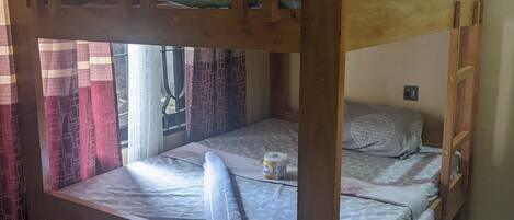 Una cama litera con dos niveles, una mesita de noche pequeña y un enchufe en la cama inferior.