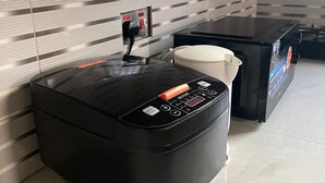 A compact kitchen with a black countertop, a coffee machine, and a small refrigerator. - Mashingo Homestay (Dar es Salaam)