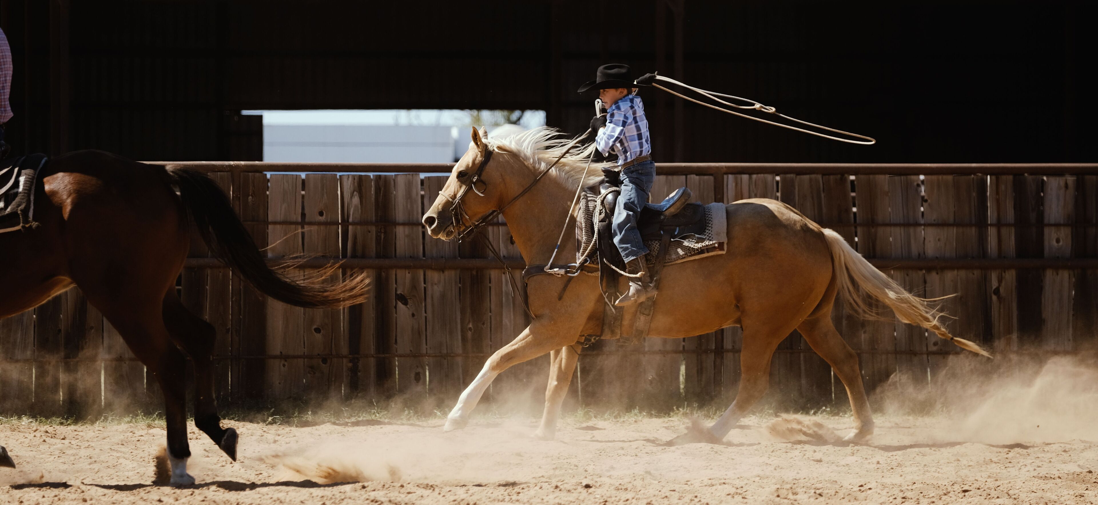A person riding a horse in an indoor arena with wooden walls.