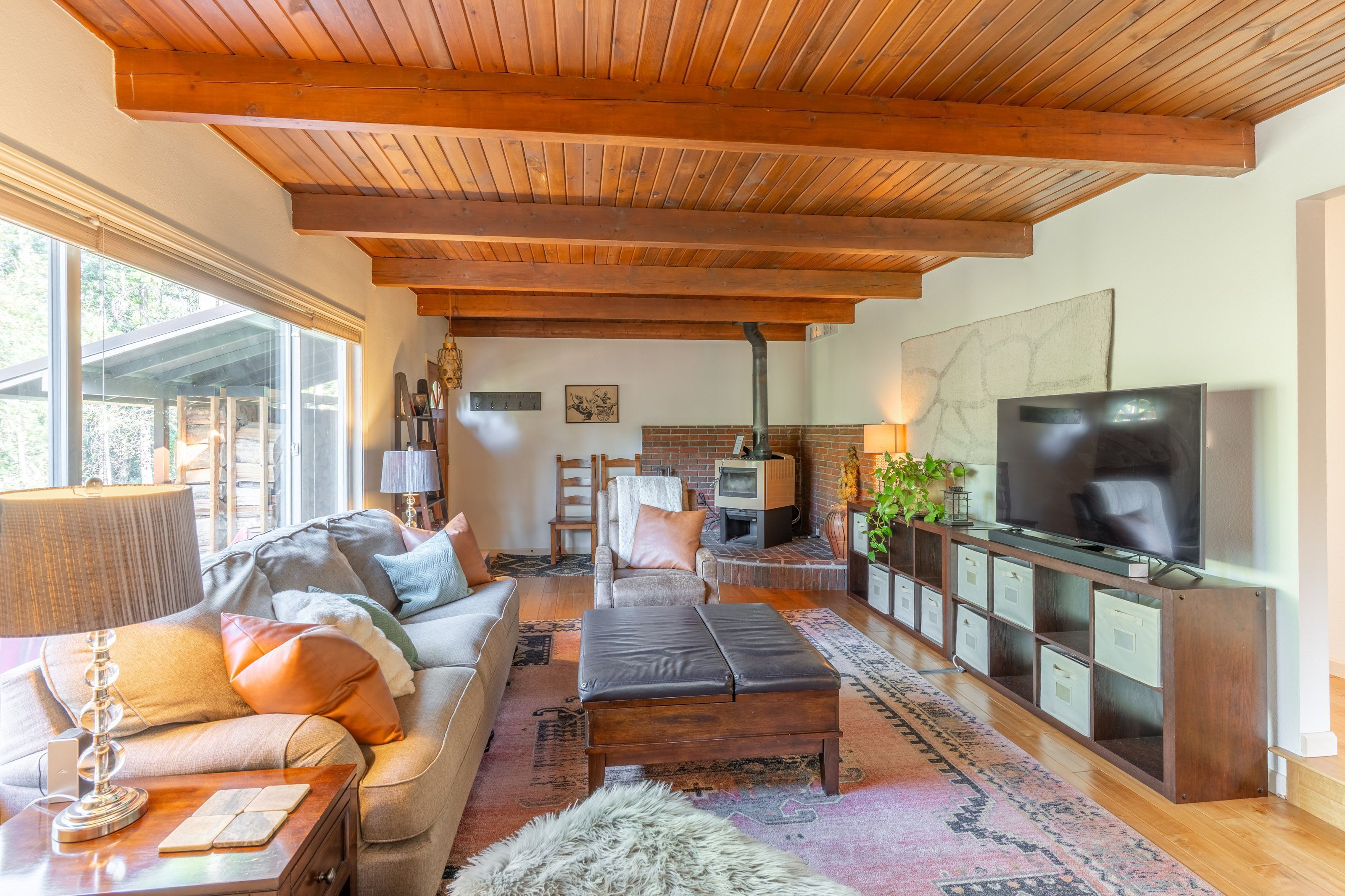 A cozy living room with a wooden ceiling, a sofa, a TV, and a fireplace.