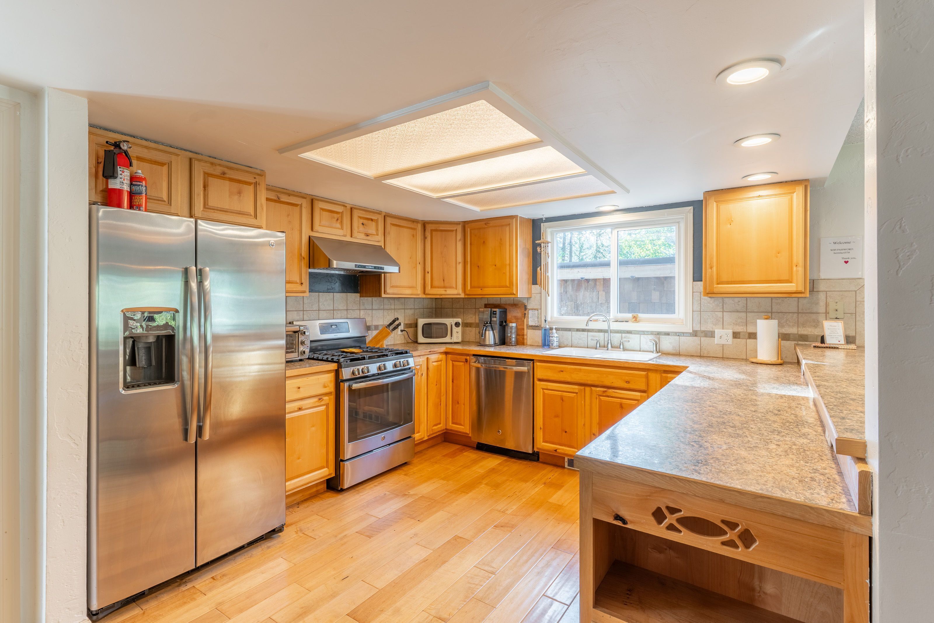 A modern kitchen with stainless steel appliances, wooden cabinets, and a large island.