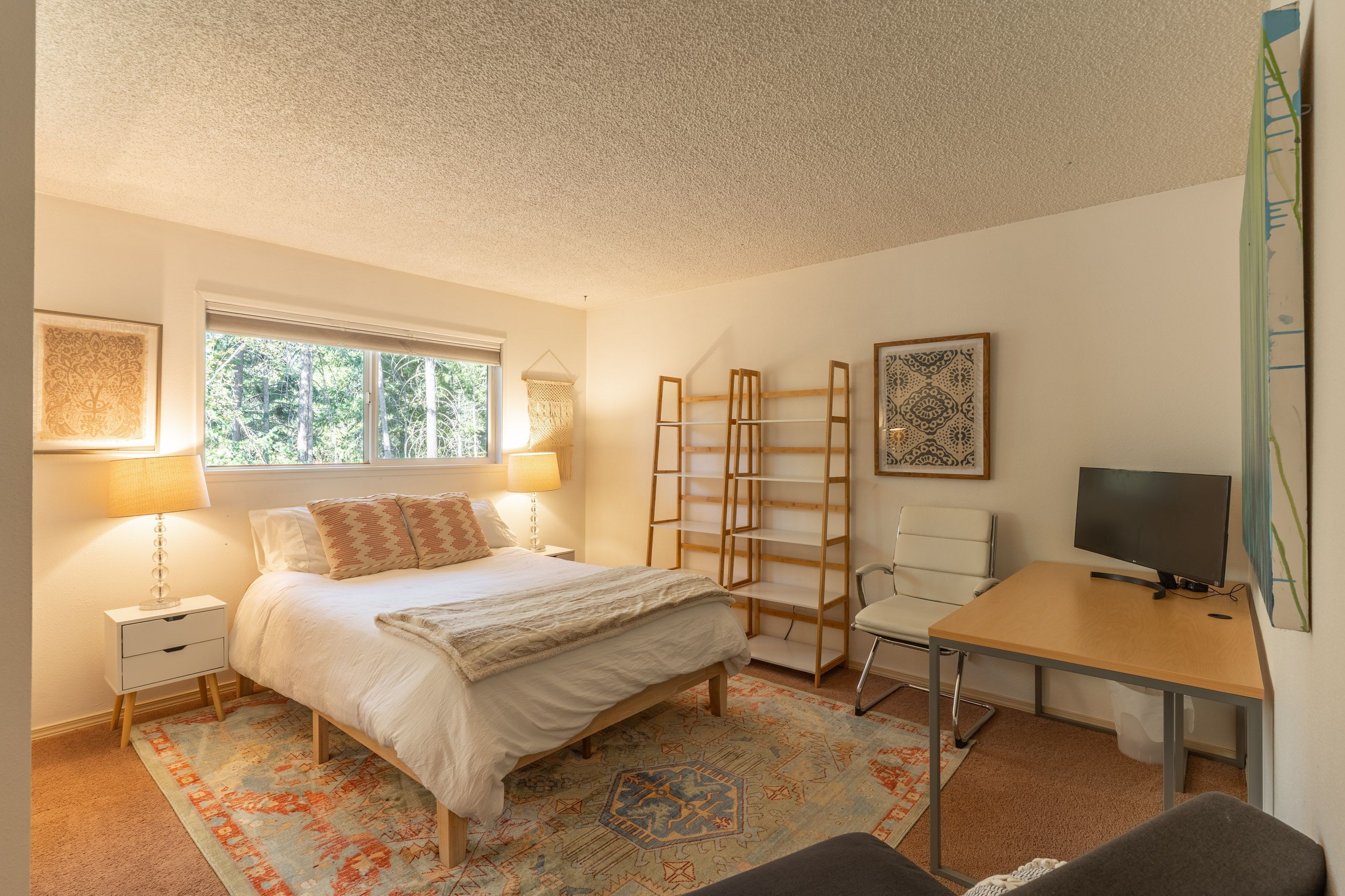 Una camera da letto con un letto, comodini, una scrivania, una sedia e una televisione.