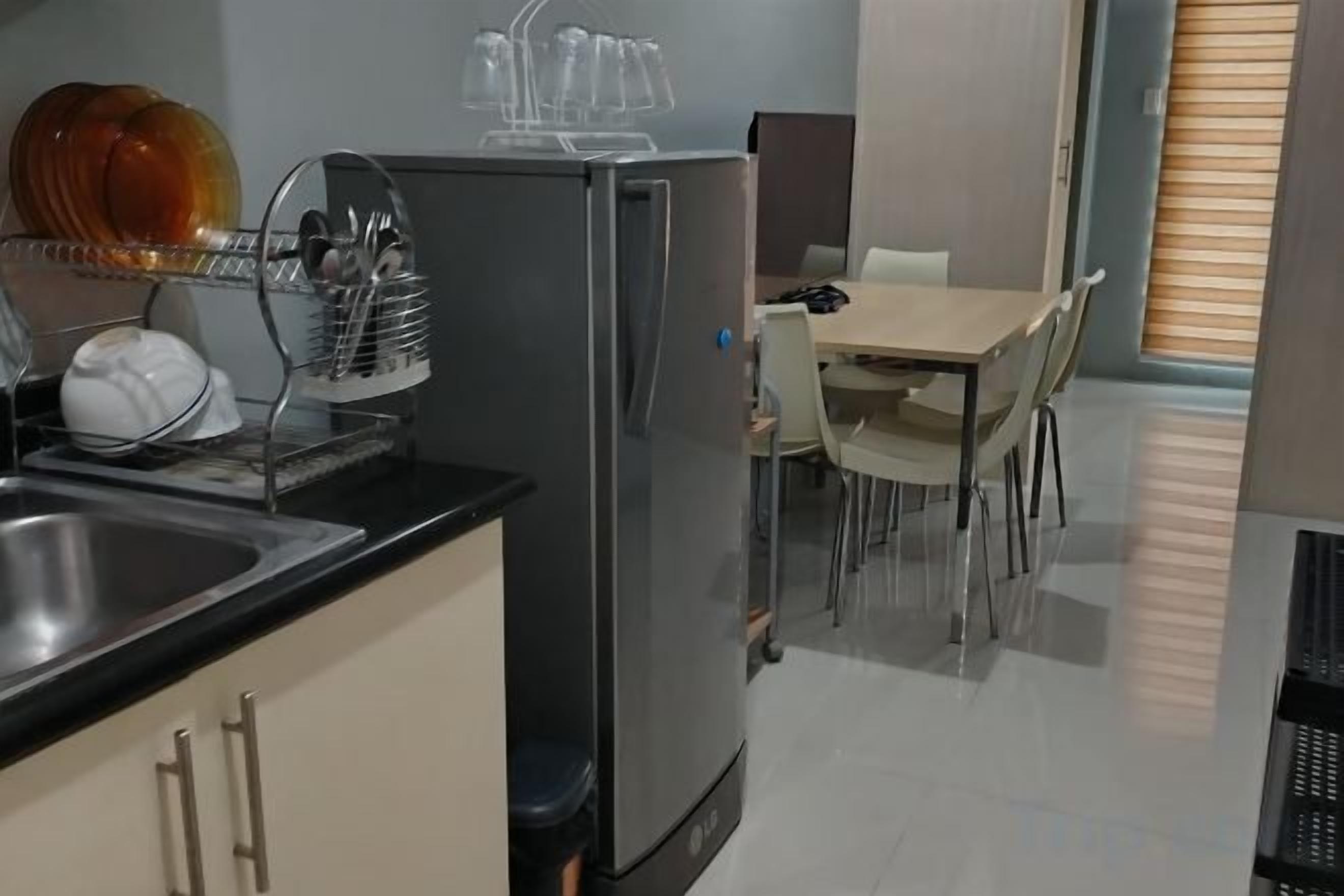 Eine kompakte Küche mit Kühlschrank, Spüle und Geschirrständer. Es gibt einen Essbereich mit Tisch und Stühlen.