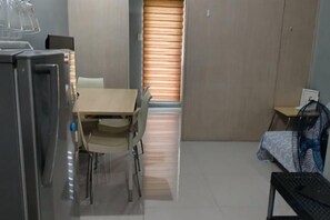 A compact room with a bed, a small desk, a chair, and a table. - Grass Residence Tower 3 20th with balcony (Quezon City)