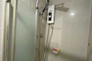 A shower area with a glass door, a handheld showerhead, and a control panel on the wall. - Grass Residence Tower 3 20th with balcony (Quezon City)