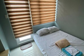 A small, neatly made bed with white bedding and a beige towel on top. - Grass Residence Tower 3 20th with balcony (Quezon City)