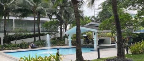 A pool area with palm trees, a gazebo, and a well-maintained lawn.