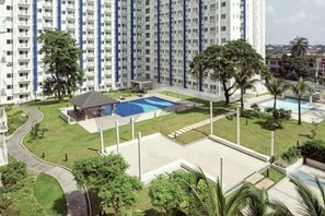 A high-rise building with multiple balconies, a swimming pool, and surrounding greenery. - Grass Residence Tower 3 20th with balcony (Quezon City)
