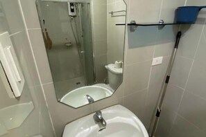 A bathroom with a sink, mirror, and shower. - Grass Residence Tower 3 20th with balcony (Quezon City)