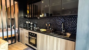 A modern kitchen with a black countertop, wooden cabinets, and a hexagonal backsplash. - Luxury Studio Apartment in Nairobi (Nairobi)