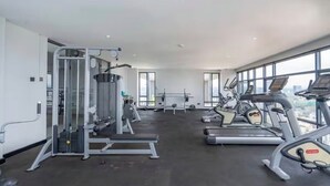 A gym with cardio machines, weightlifting equipment, and large windows. - Luxury Studio Apartment in Nairobi (Nairobi)