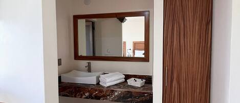 Un baño con un lavamanos blanco, un espejo y una puerta de madera.
