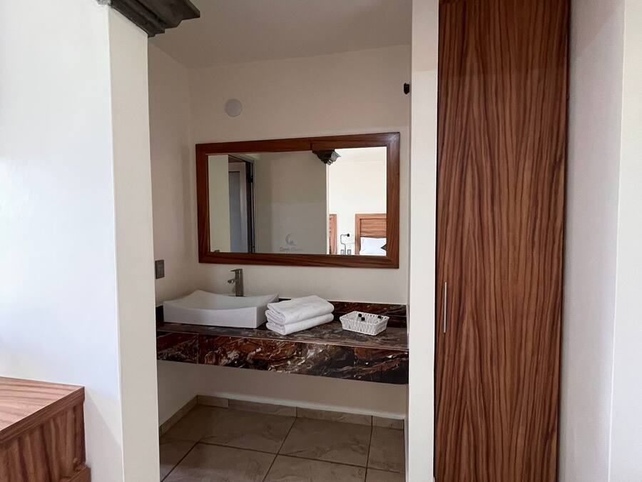A bathroom with a white sink, a mirror, and a wooden door.