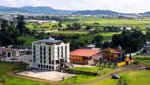 A large building with multiple floors, a courtyard, and a bridge connecting to another structure. - Quinta Candela Hotel (Chignahuapan)