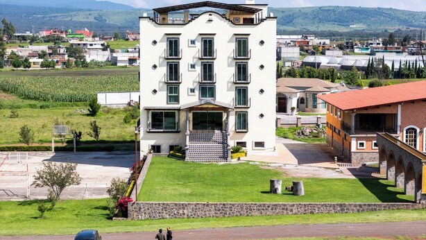 A multi-story building with a flat roof, large windows, and a stone facade. - Quinta Candela Hotel (Chignahuapan)