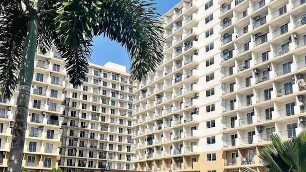 A high-rise hotel with multiple balconies, a swimming pool, and lush greenery. - Cheap Accommodation - Saekyung Apartment (Lapu-Lapu)