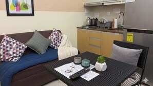 Un espacio habitable compacto con sofá, una pequeña mesa de comedor y una kitchenette.