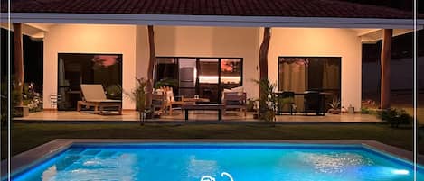 A villa with a swimming pool, outdoor seating, and a covered patio area.