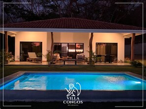 A villa with a swimming pool, outdoor seating, and a covered patio area.