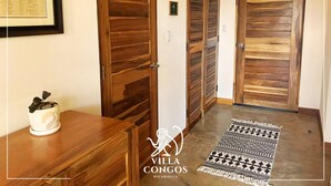 A hallway with wooden doors, a framed certificate on the wall, and a patterned rug on the floor.