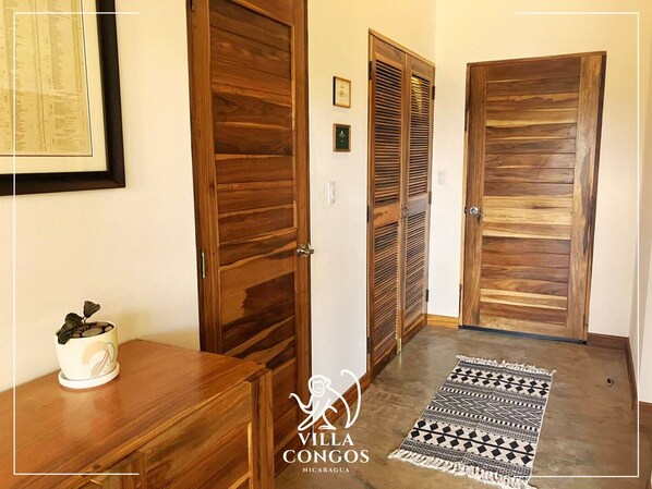 Un couloir avec des portes en bois, un certificat encadré accroché au mur et un tapis à motifs sur le sol.