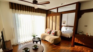 Ein Hotelzimmer mit Bett, einer Couch, einem Esstisch mit Schüsseln und einem Deckenventilator.