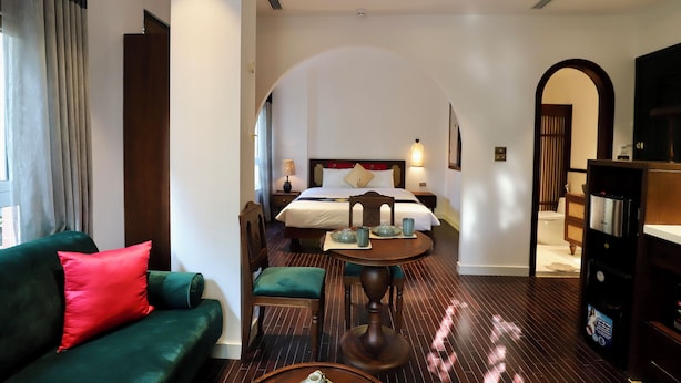 Ein Hotelzimmer mit einem Bett, einer grünen Couch, einem Esstisch und einer kleinen Küchenzeile.