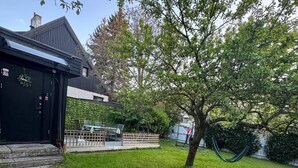 Un cortile residenziale con prato, un albero e un capanno nero.