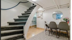 Una scala conduce a una stanza con zona pranzo, uno specchio rotondo e un condizionatore d'aria a parete.