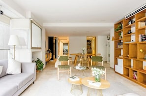 Uma sala de estar moderna com um sofá, cadeiras, uma mesa de centro e uma estante.