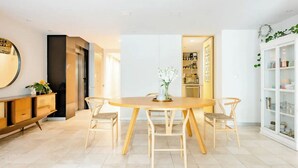 Ein Essbereich mit Holztisch, vier Stühlen, einem weißen Schrank mit Glastüren und einem Spiegel an der Wand.