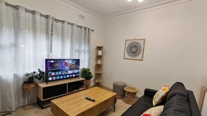 A living room with a TV, sofa, coffee table, and a plant.