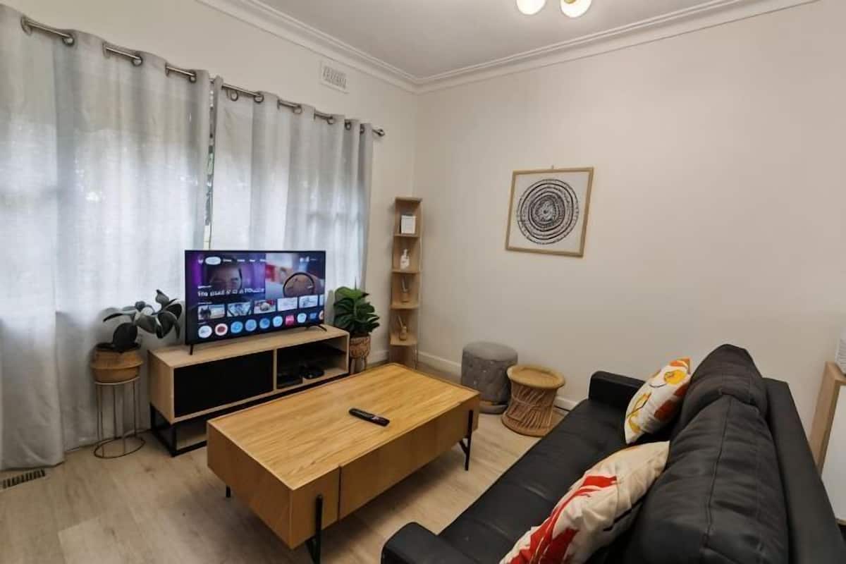 A living room with a TV, sofa, coffee table, and a plant.