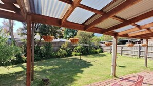 A covered outdoor area with a patio, a brick table, and hanging baskets.