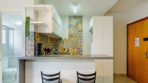 Una cocina pequeña con salpicadero de azulejos, una cafetera y dos sillas.
