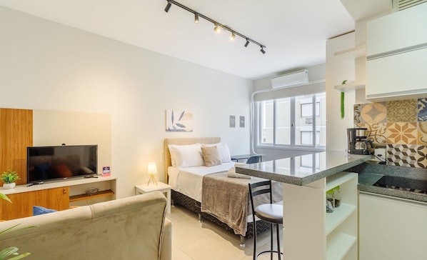Una habitación de hotel moderna con cama, televisión, escritorio y kitchenette.