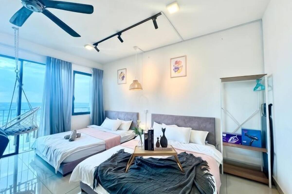 Ein Hotelzimmer mit zwei Betten, einem Deckenventilator, Meerblick und einem Balkon mit einer Hängematte.