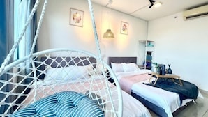 Una habitación con una silla colgante, una cama con almohada azul y blanca a rayas, una mesita de noche con lámpara y un estante en la pared con objetos decorativos.
