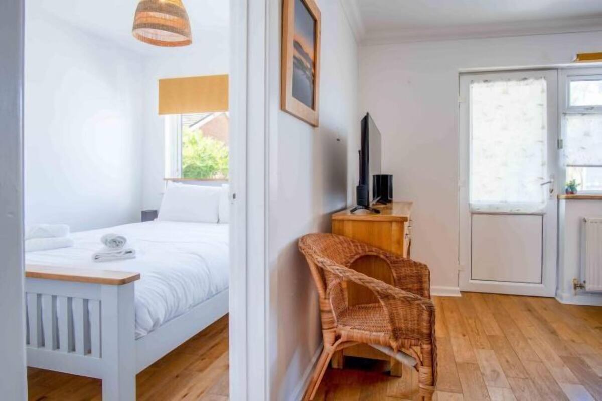 A bedroom with a bed, a chair, a television, and a window.