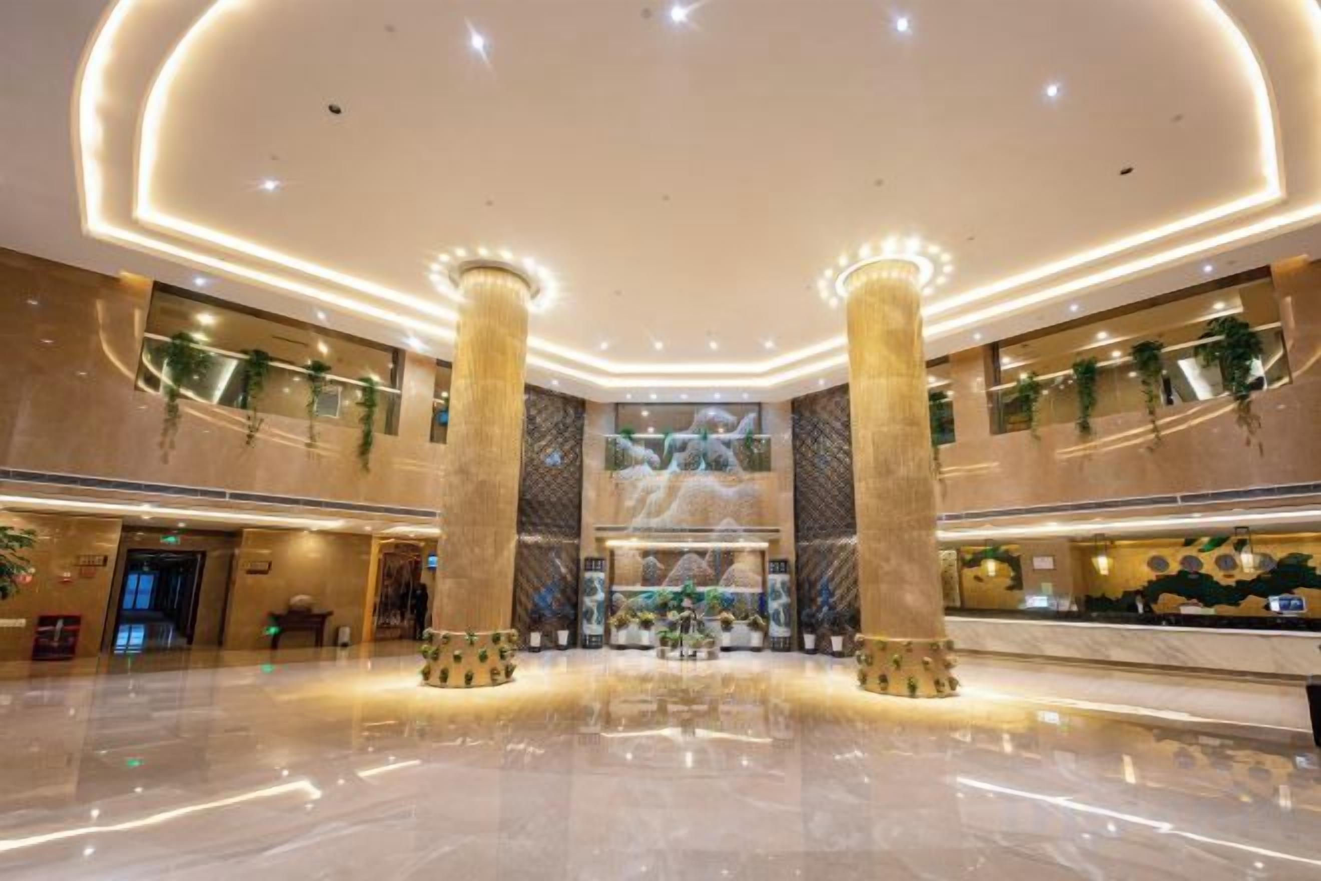 A spacious lobby with high ceilings, large columns, and a central decorative fountain.