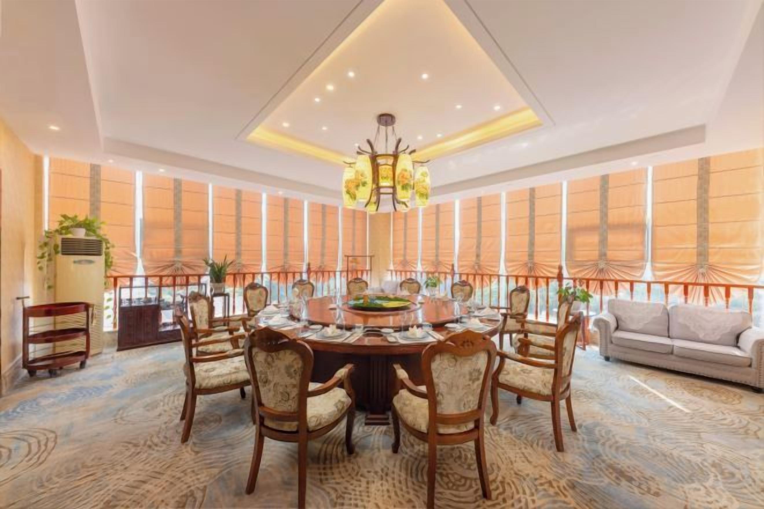 A dining area with a round table, chairs, and a chandelier.
