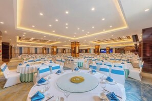 A banquet hall with round tables, white chairs, and blue sashes. - Bai an Hotel (Chongqing)
