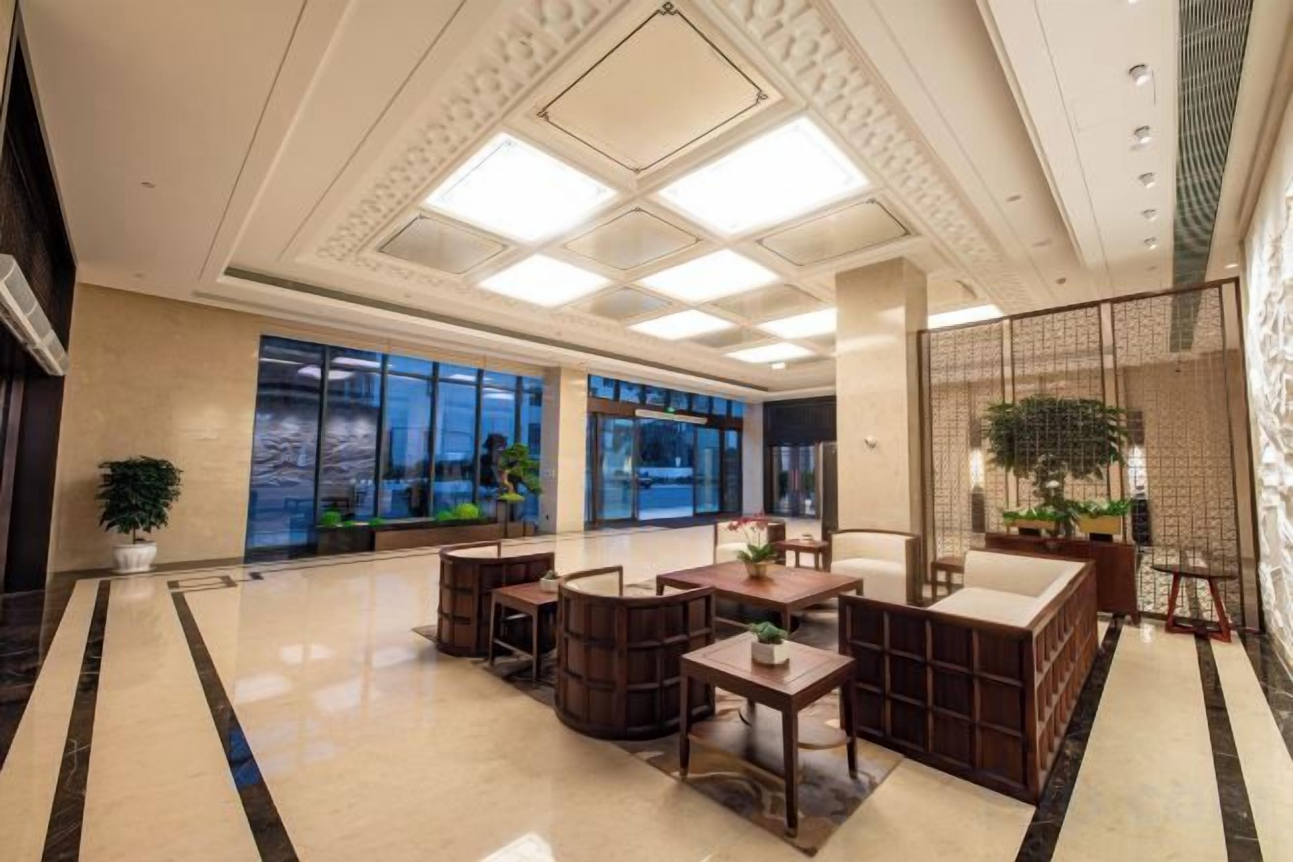 A hotel lobby with a reception desk, seating area, and large windows.