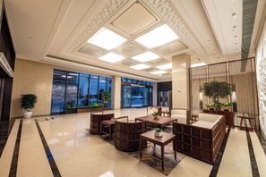 A hotel lobby with a reception desk, seating area, and large windows. - Bai an Hotel (Chongqing)