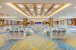 A large banquet hall with rows of round tables, white chairs, and a blue carpet. - Bai an Hotel (Chongqing)